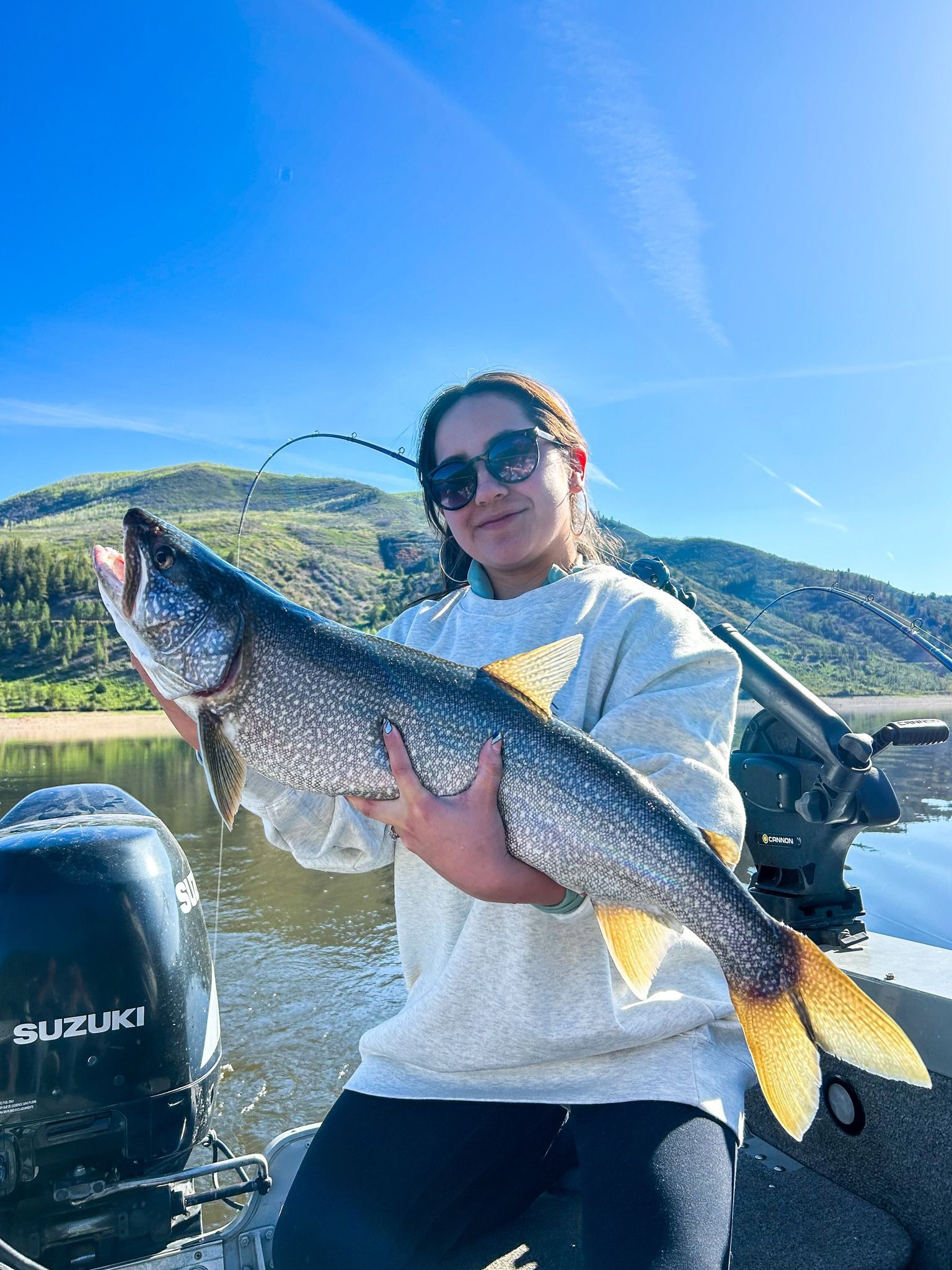 A woman is sitting on a boat holding a large fish.
