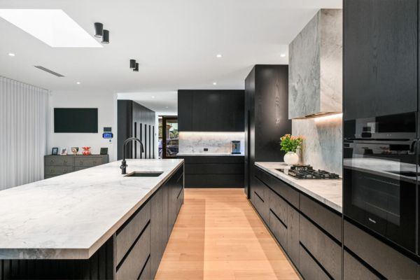 Modern black and white kitchen with long island and wooden floor — PK Kitchen Design in West Ipswich, QLD