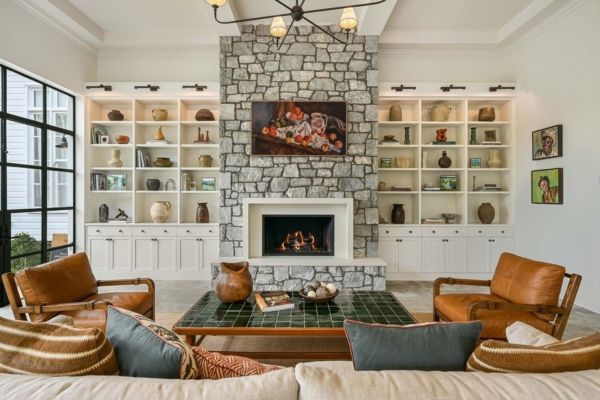 Living room with stone fireplace, built-in shelves, leather chairs, and a tiled coffee table — PK Kitchen Design in West Ipswich, QLD