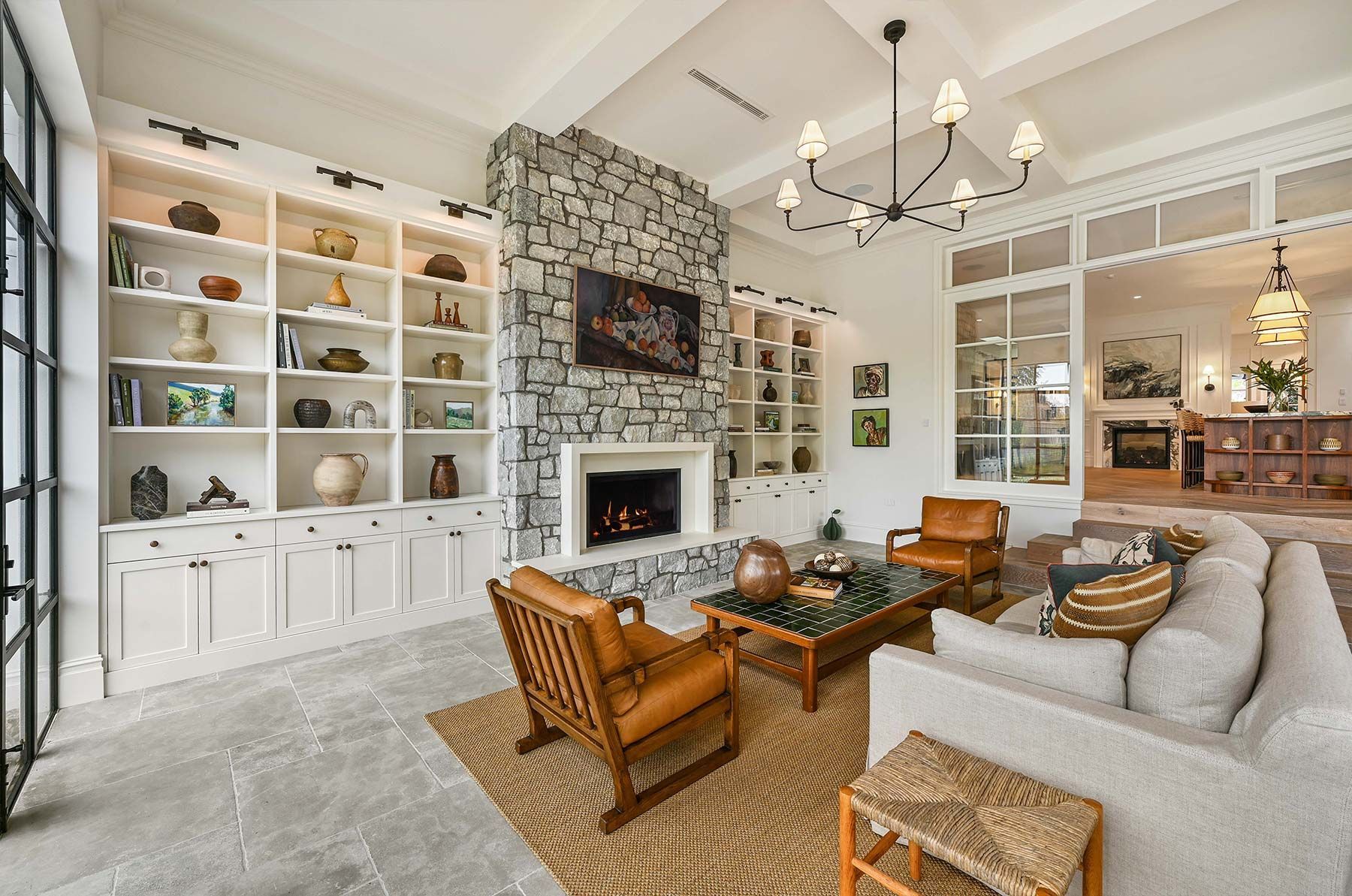 Living room with stone fireplace, built-in shelves, tan sofa, and armchairs — PK Kitchen Design in West Ipswich, QLD