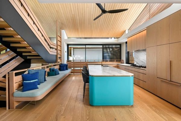 Modern kitchen with turquoise island, wooden cabinets, and a staircase with a built-in bench — PK Kitchen Design in West Ipswich, QLD