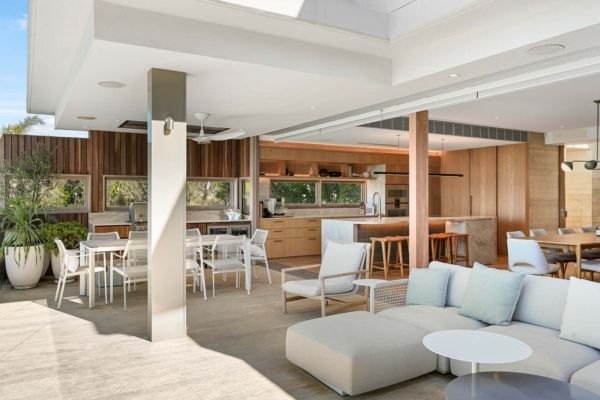 Outdoor kitchen and living space with a sofa, dining table, and bar, featuring light wood and neutral tones — PK Kitchen Design in West Ipswich, QLD