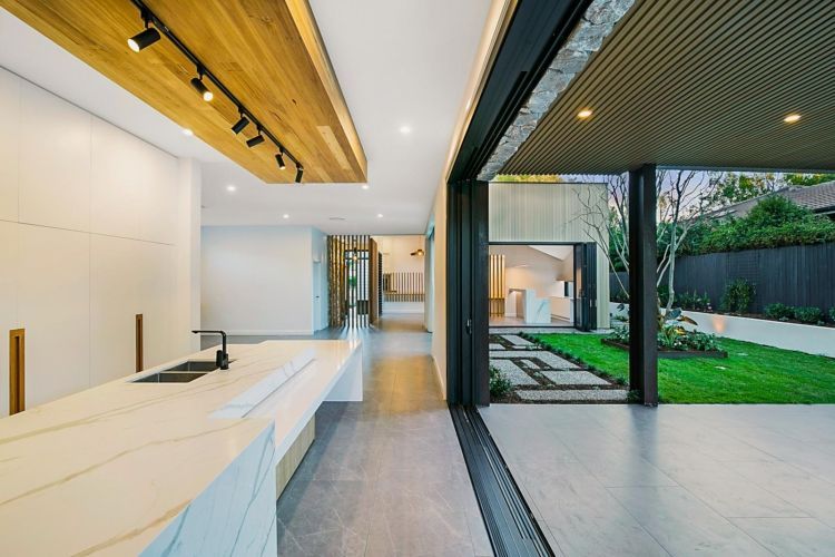 Modern kitchen with marble island, open to a backyard patio with greenery — PK Kitchen Design in West Ipswich, QLD