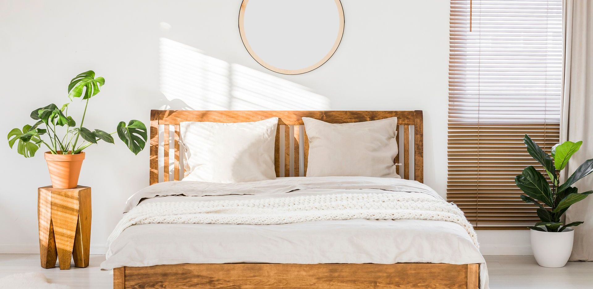 A bedroom with a wooden bed , plants , and a window.