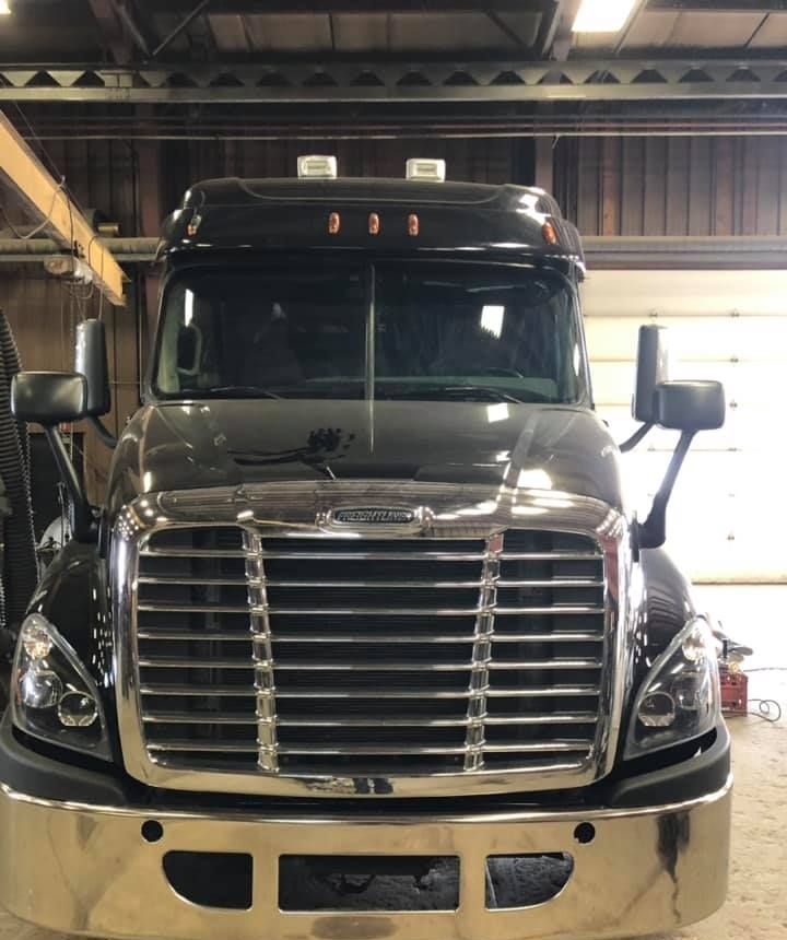 A black truck with a chrome bumper is parked in a garage