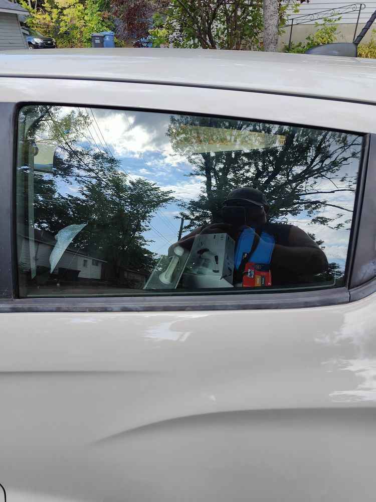 A person is taking a picture of their reflection in a car window.