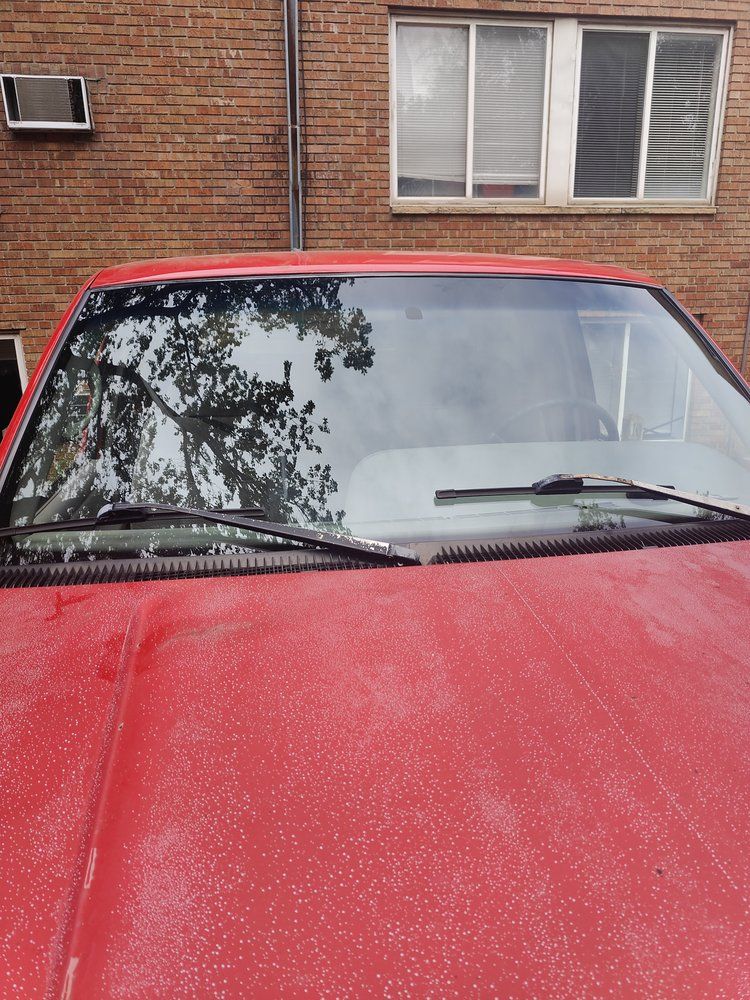 A red car is parked in front of a brick building