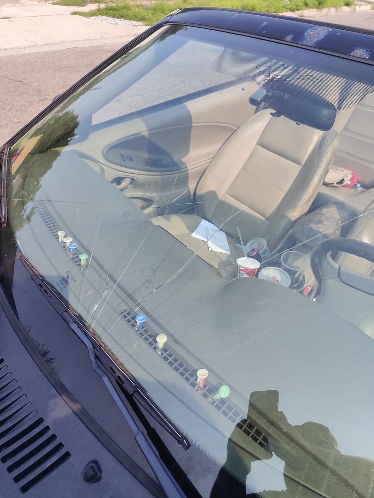 A car with a broken windshield is parked on the side of the road