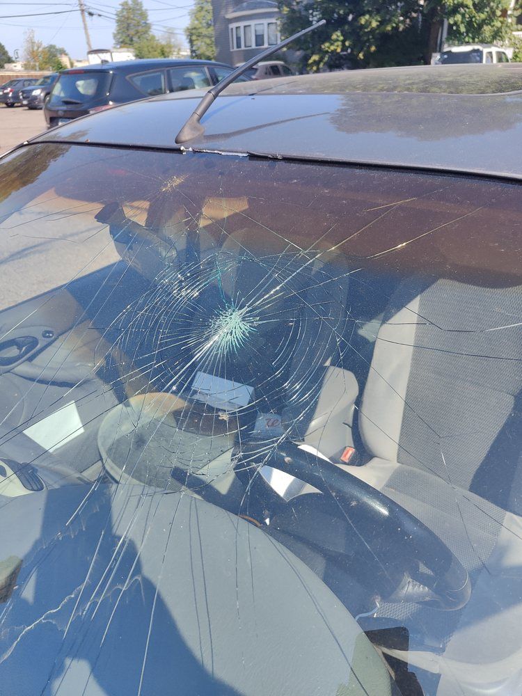 A car with a broken windshield is parked in a parking lot.