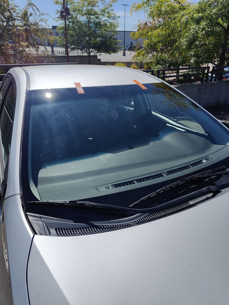 A white car with a broken windshield is parked in a parking lot.