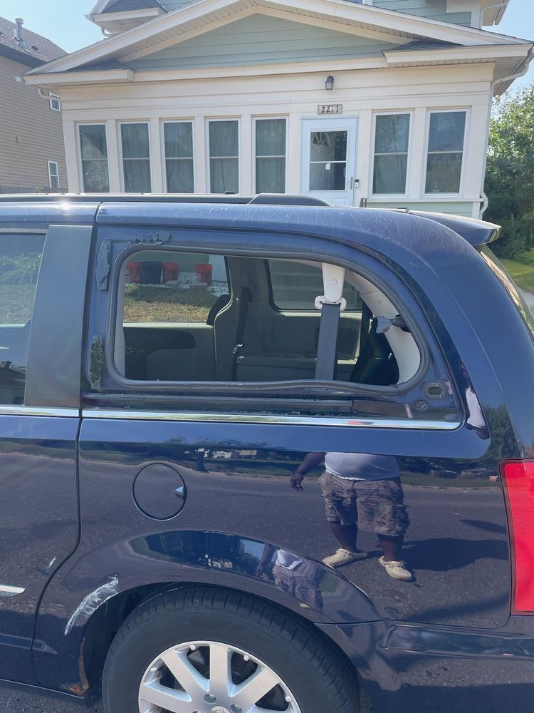 A black minivan is parked in front of a house.