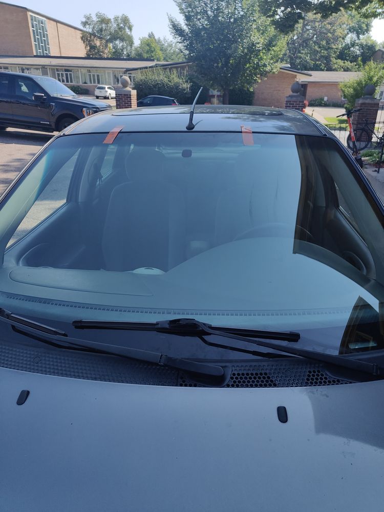 A car with a red stripe on the windshield is parked in a parking lot.