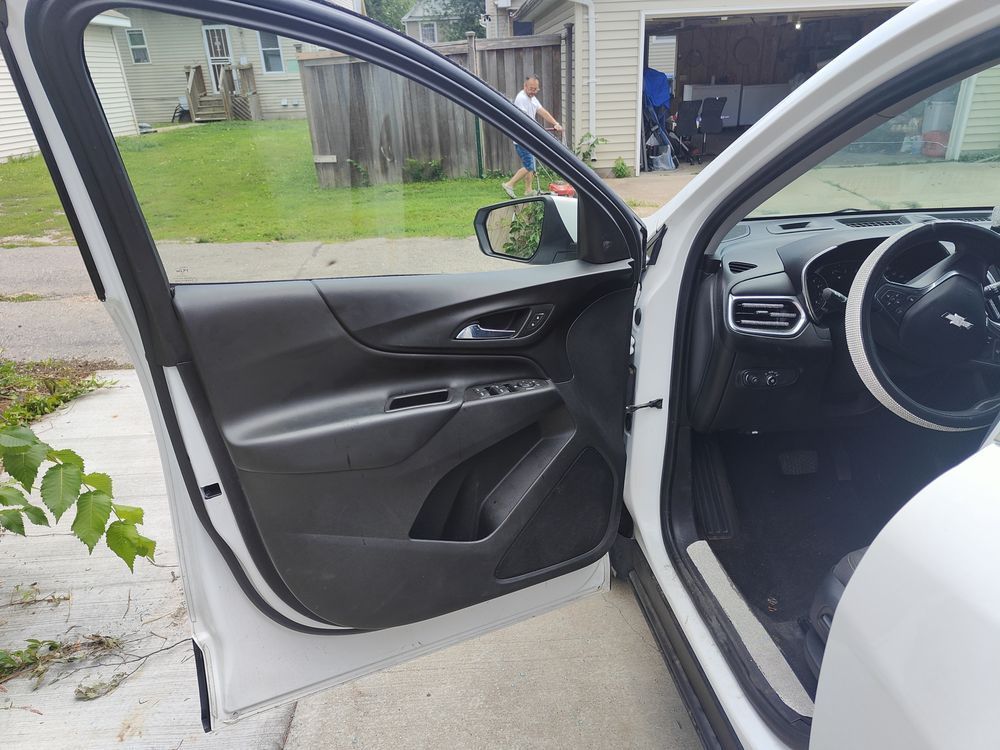 A white car is parked in a driveway with the door open