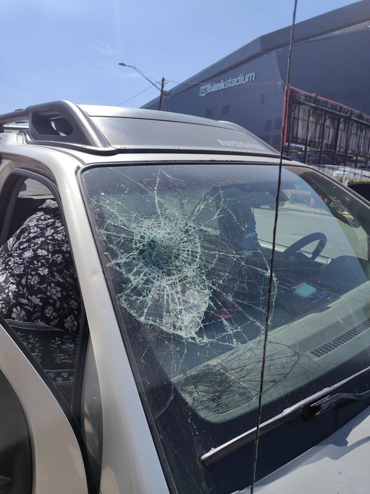 A car with a broken windshield is parked in front of a building.