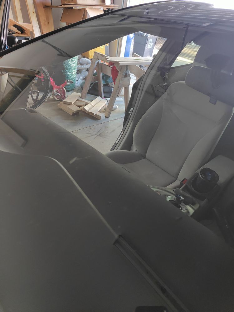 A car with a broken windshield is parked in a garage.