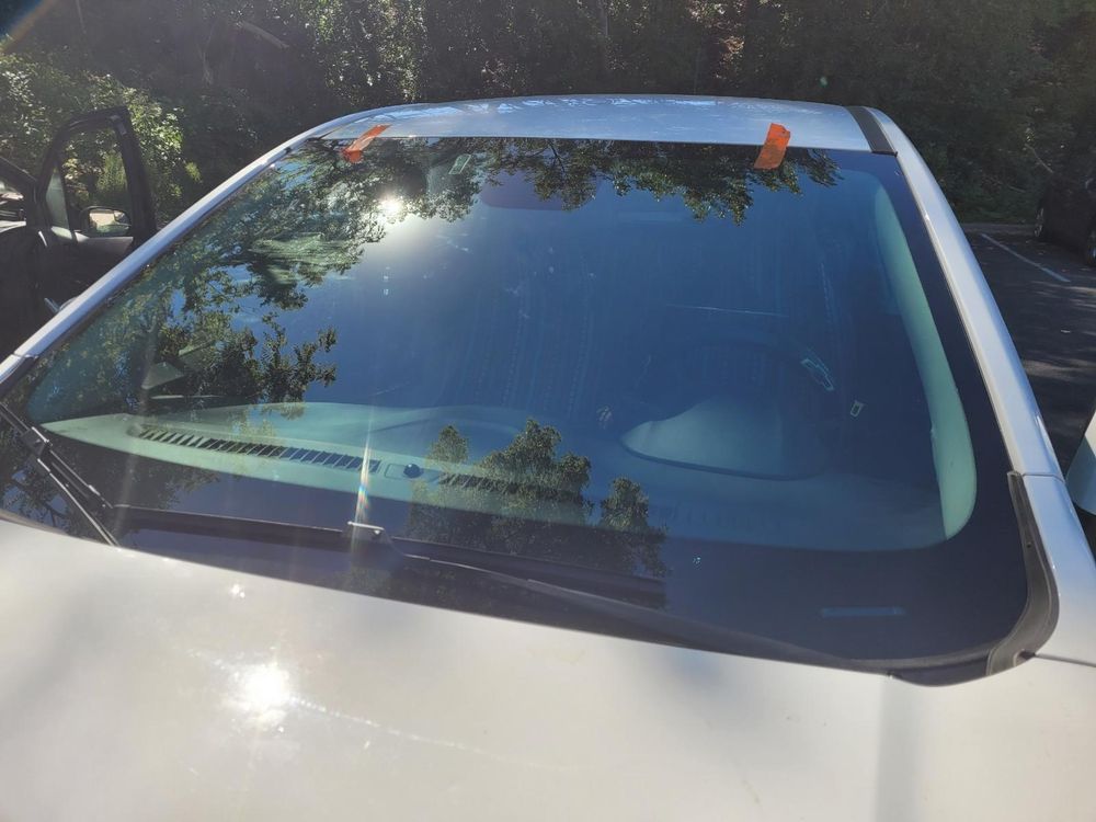 A white car with a broken windshield is parked in a parking lot.