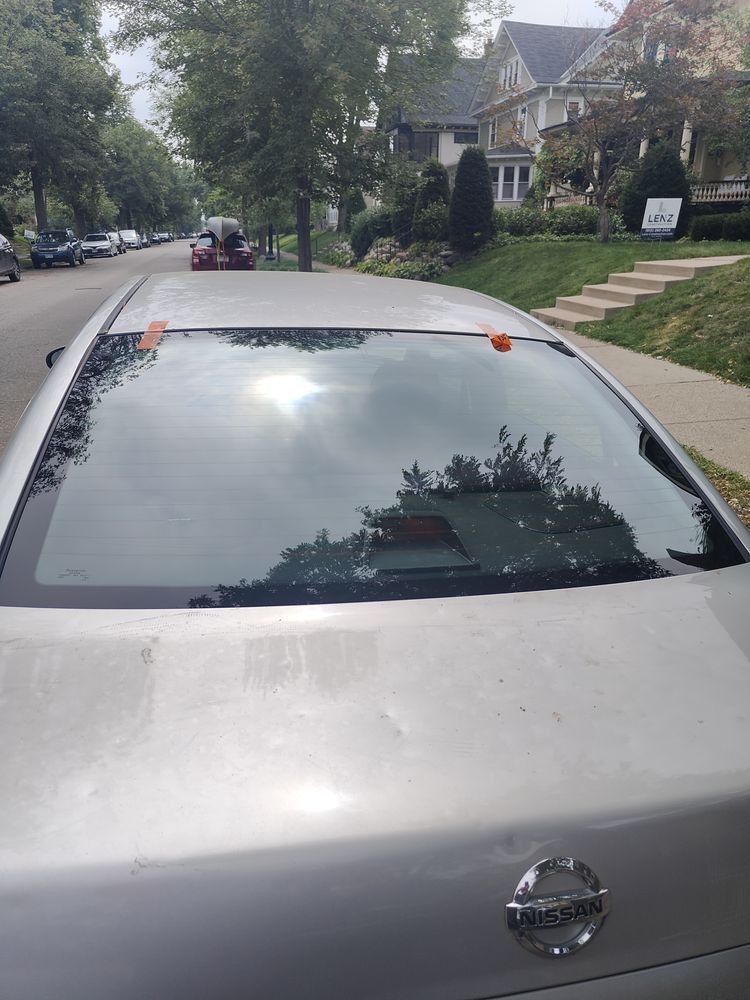A silver nissan car is parked on the side of the road
