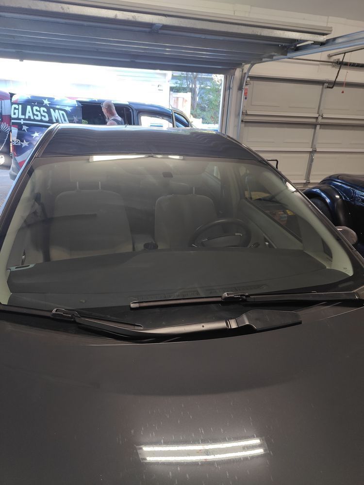 A car with a new windshield is parked in a garage.
