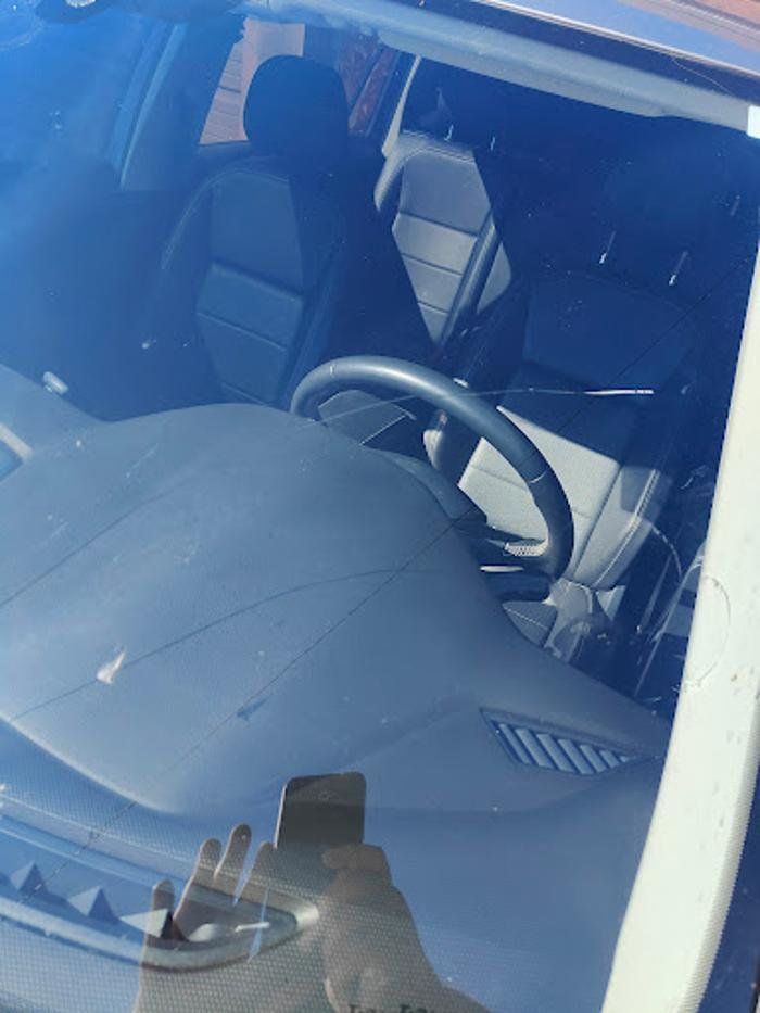 A steering wheel is visible through the windshield of a car