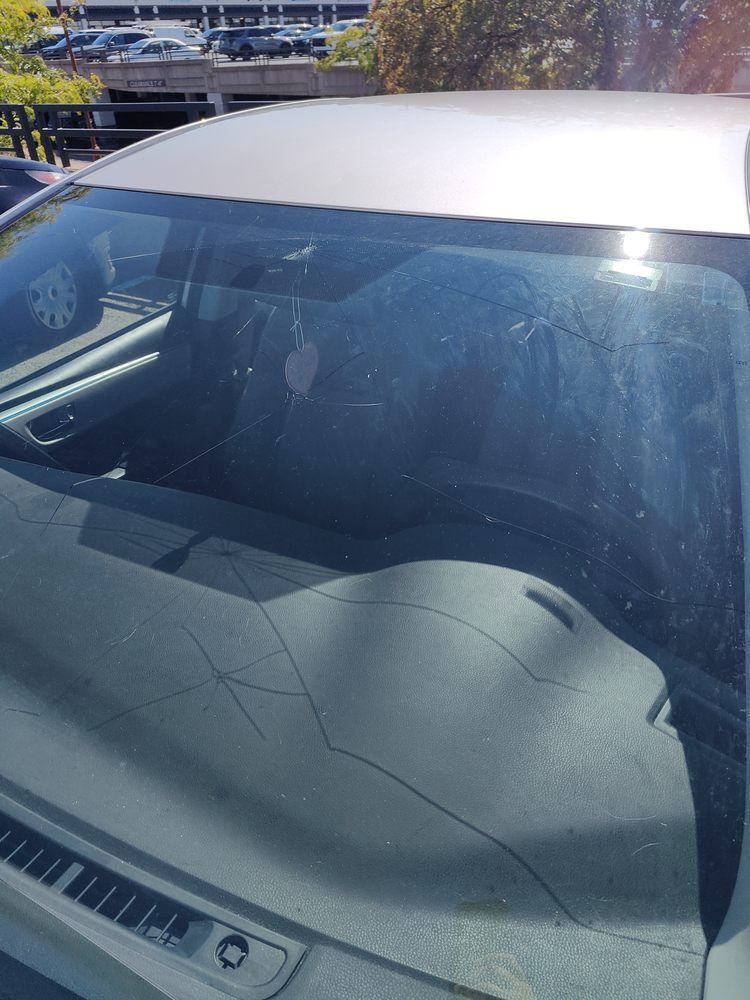 A car with a cracked windshield is parked in a parking lot