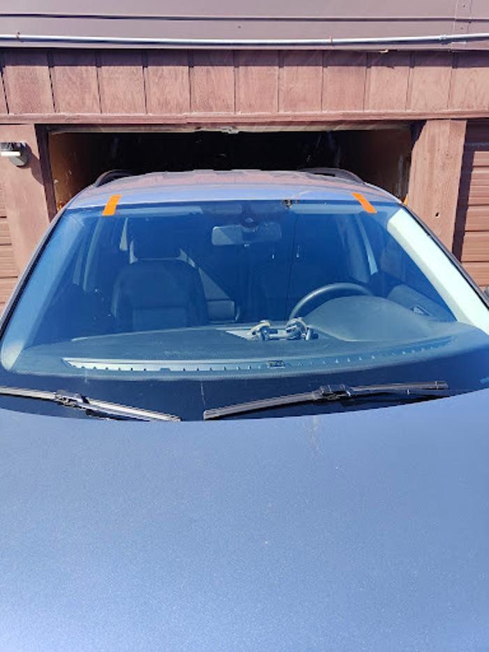 A car is parked in a garage with a sticker on the windshield.