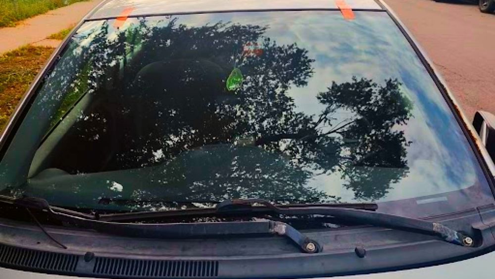 A car with a broken windshield is parked on the side of the road.