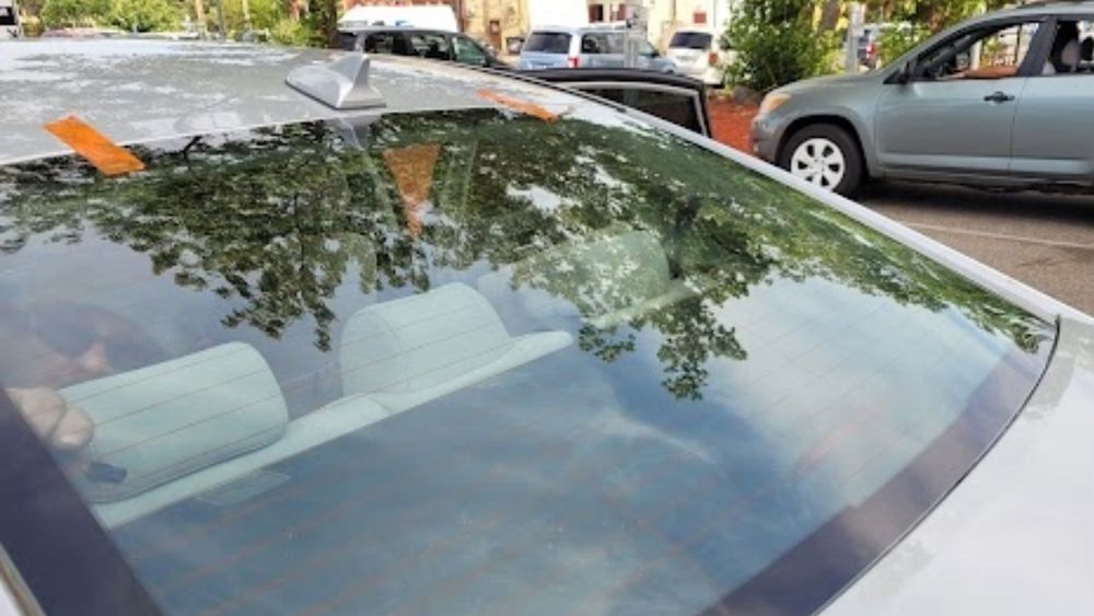 A car with a sticker on the windshield is parked in a parking lot.