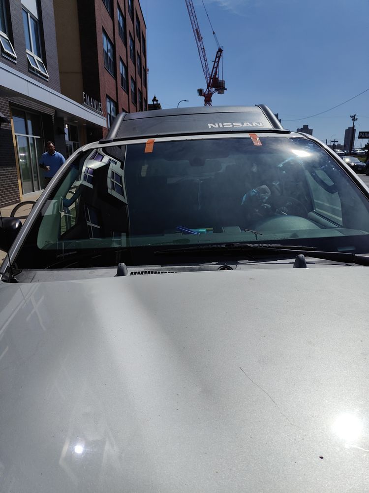 A silver car is parked in front of a building with a crane in the background