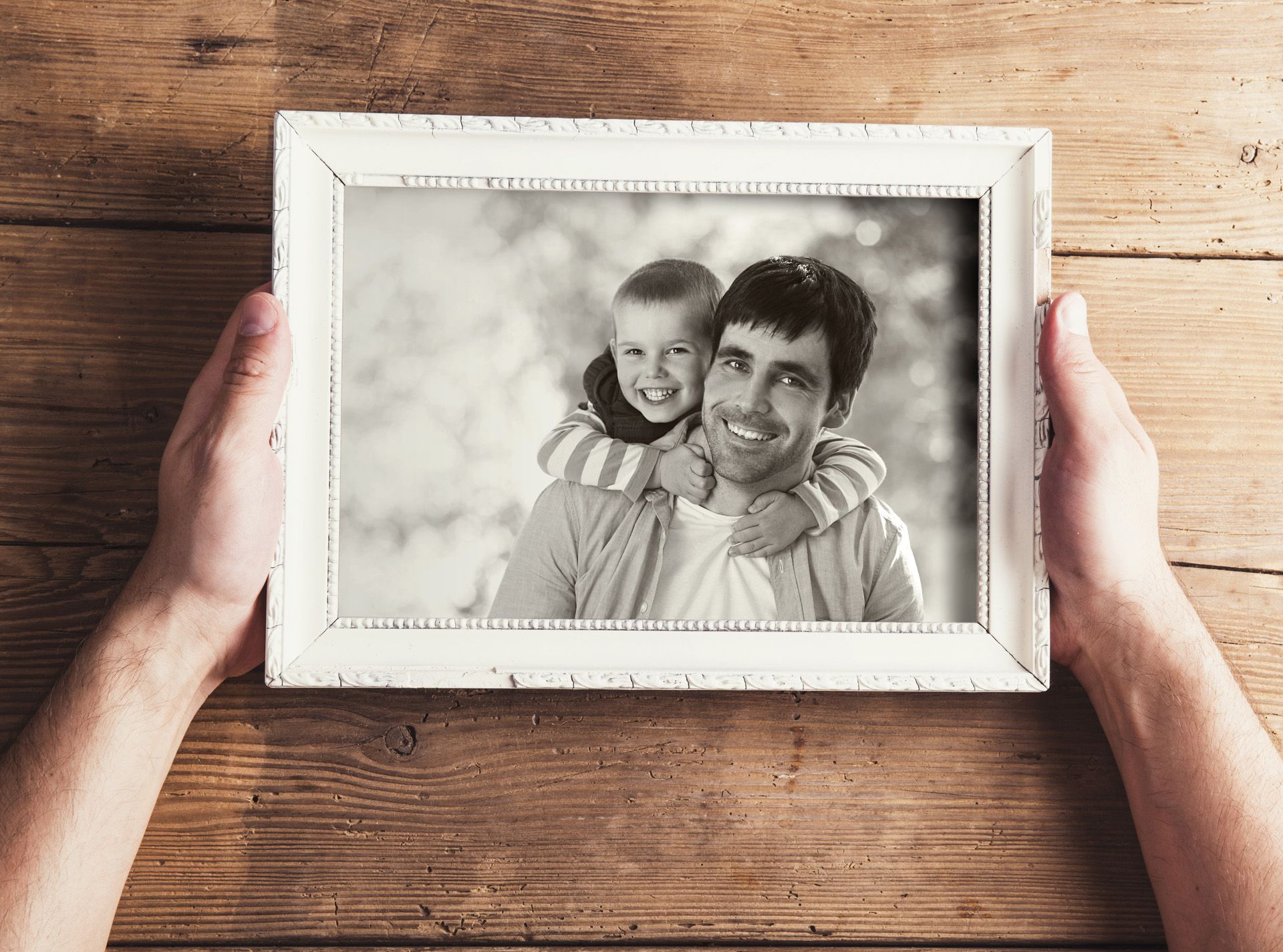 Father holding frame of him and his young son, black and white photo.