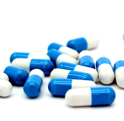 Uma pilha de cápsulas azuis e brancas sobre uma superfície branca