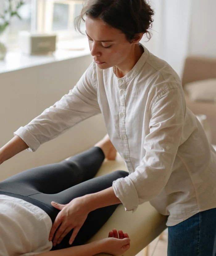 A woman is giving a massage to a woman laying on a bed.