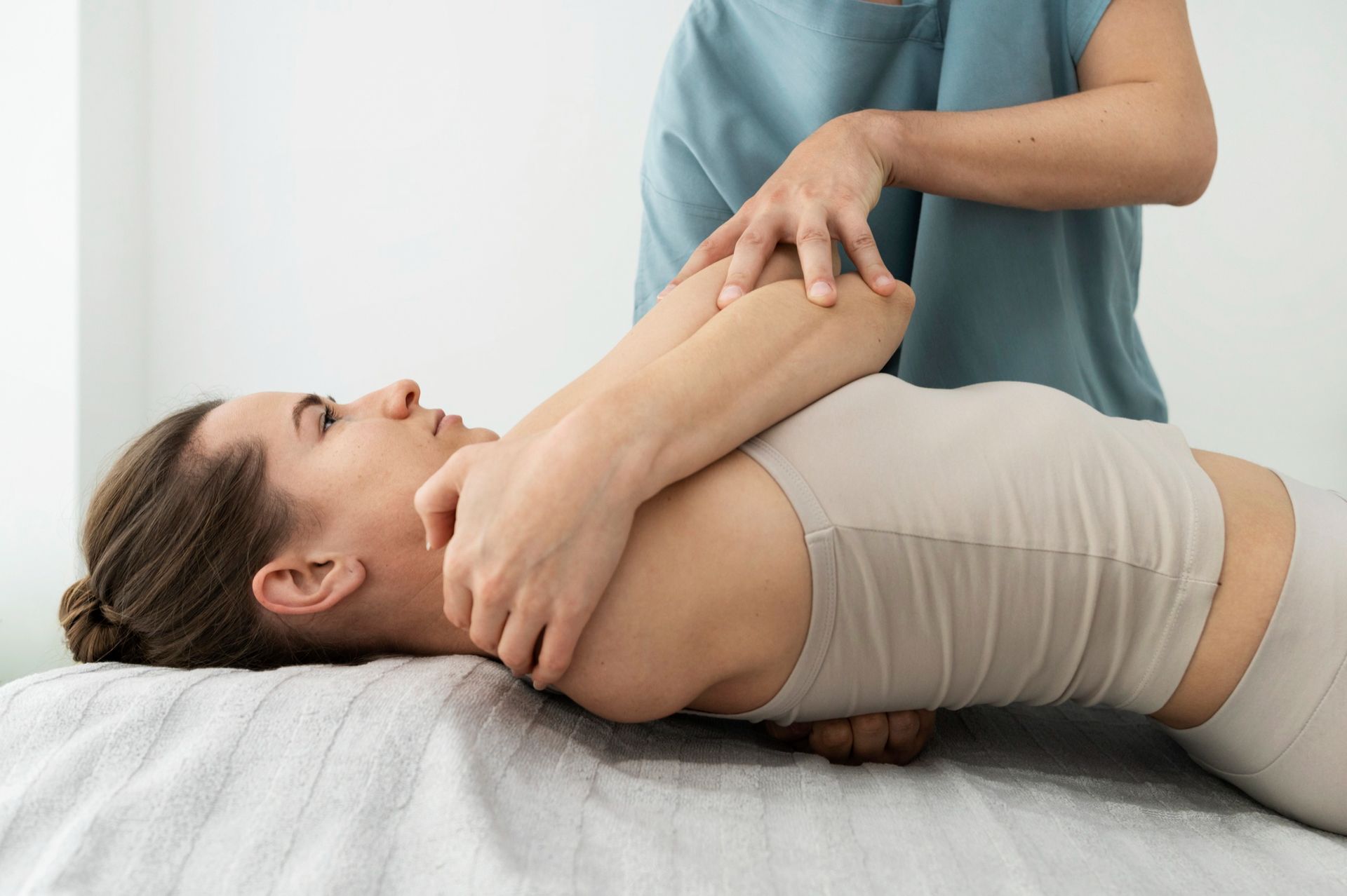 A woman is laying on a bed getting a massage from a doctor.