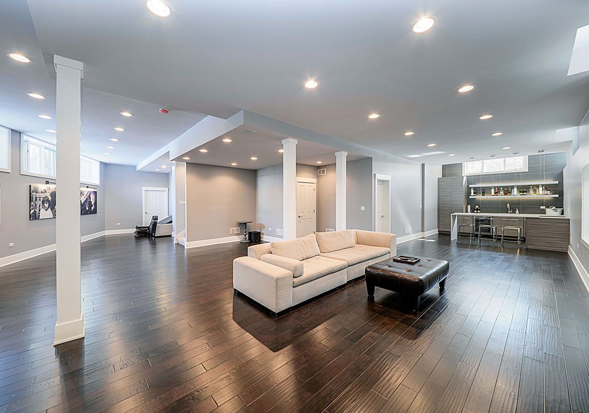 Spacious modern living room with dark wood floors, white sofa, and recessed ceiling lights