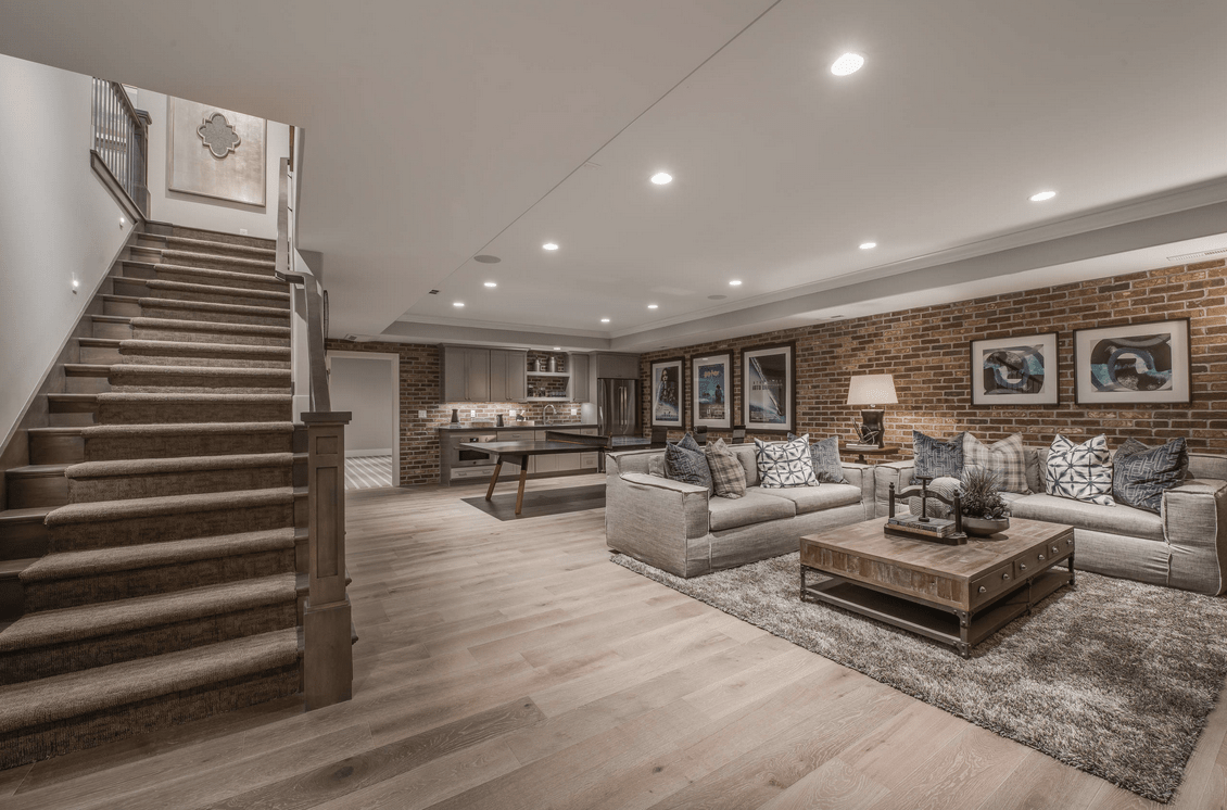 Spacious modern living room with staircase, gray sofas, coffee table, and recessed ceiling lights