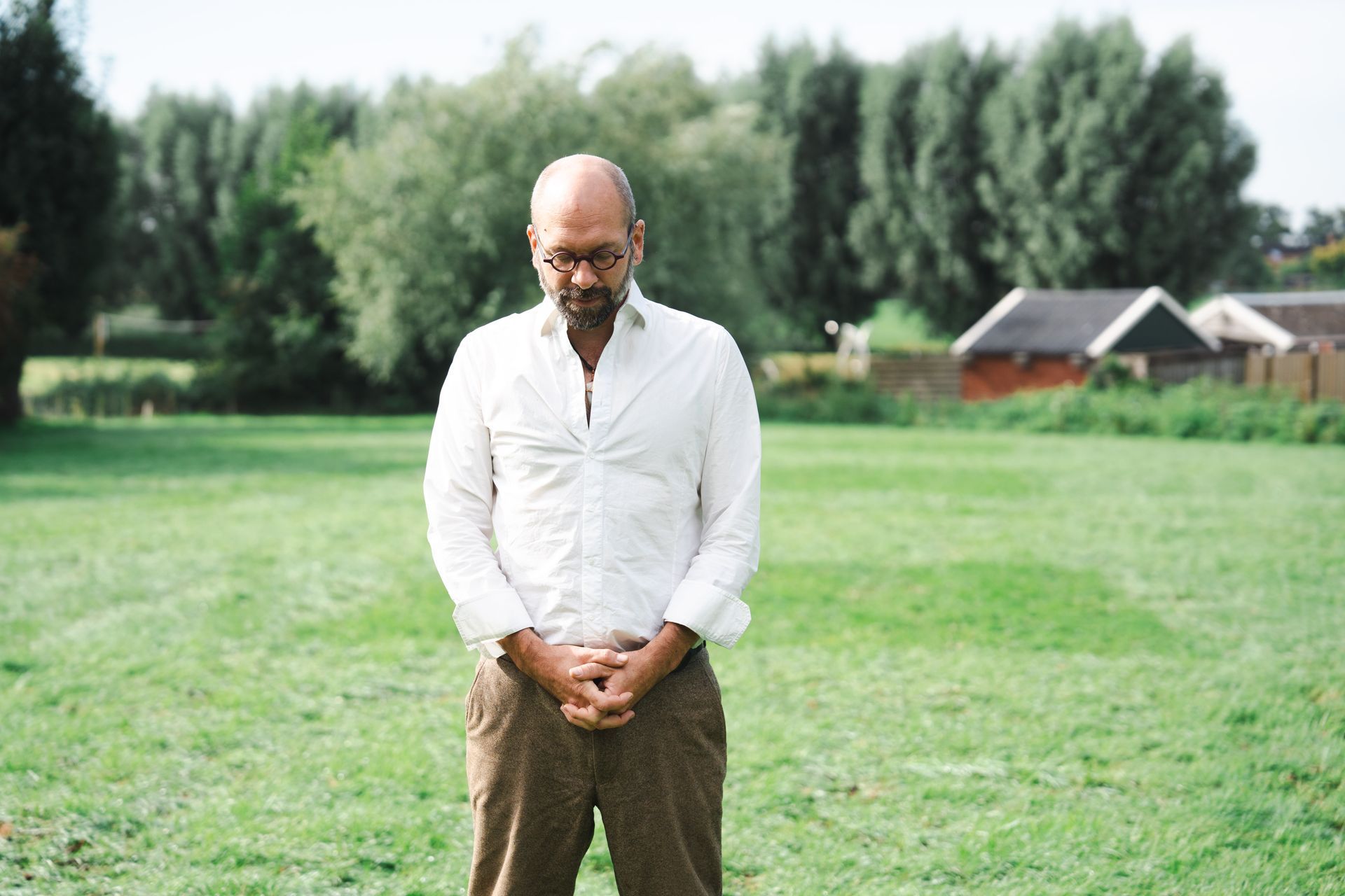 Bas van der Tang zit op een houten bankje tegen een bakstenen muur.