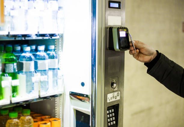 Close-up of a man’s hands using a credit card to pay for a vending machine item.