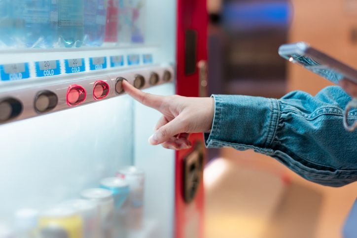 A person is using a vending machine to buy a drink.