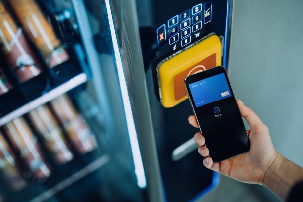 A person is holding a cell phone in front of a vending machine.