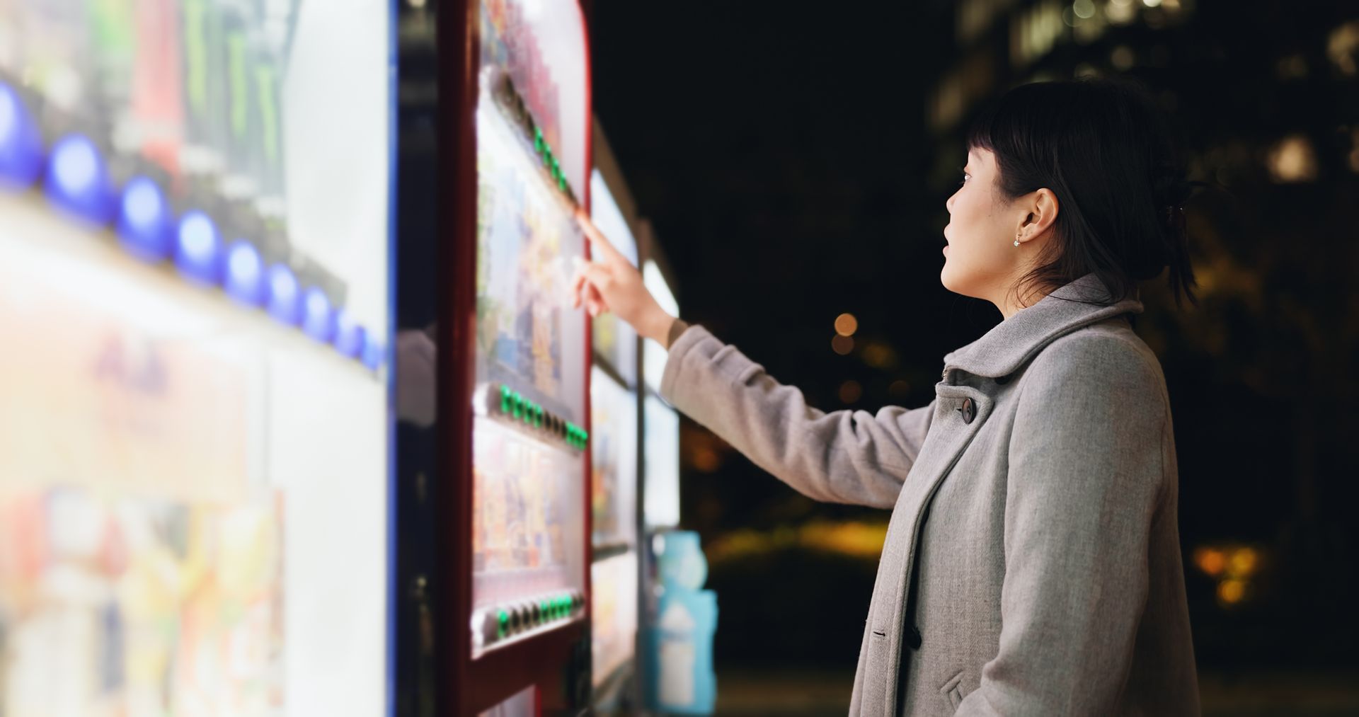 A woman is using a vending machine at night. A woman is using a vending machine at night.