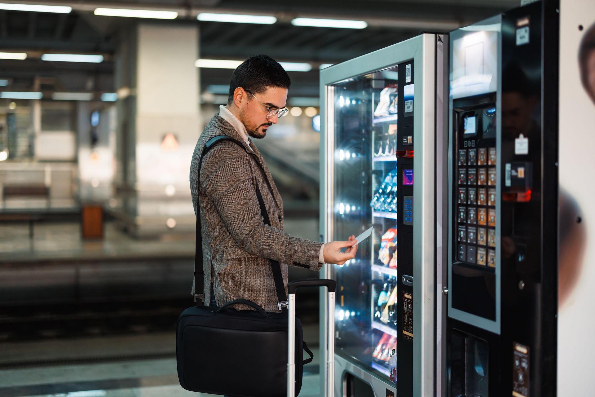 A businessman with glasses grabs a healthy snack from a sleek fresh market vending machine. A businessman with glasses grabs a healthy snack from a sleek fresh market vending machine.