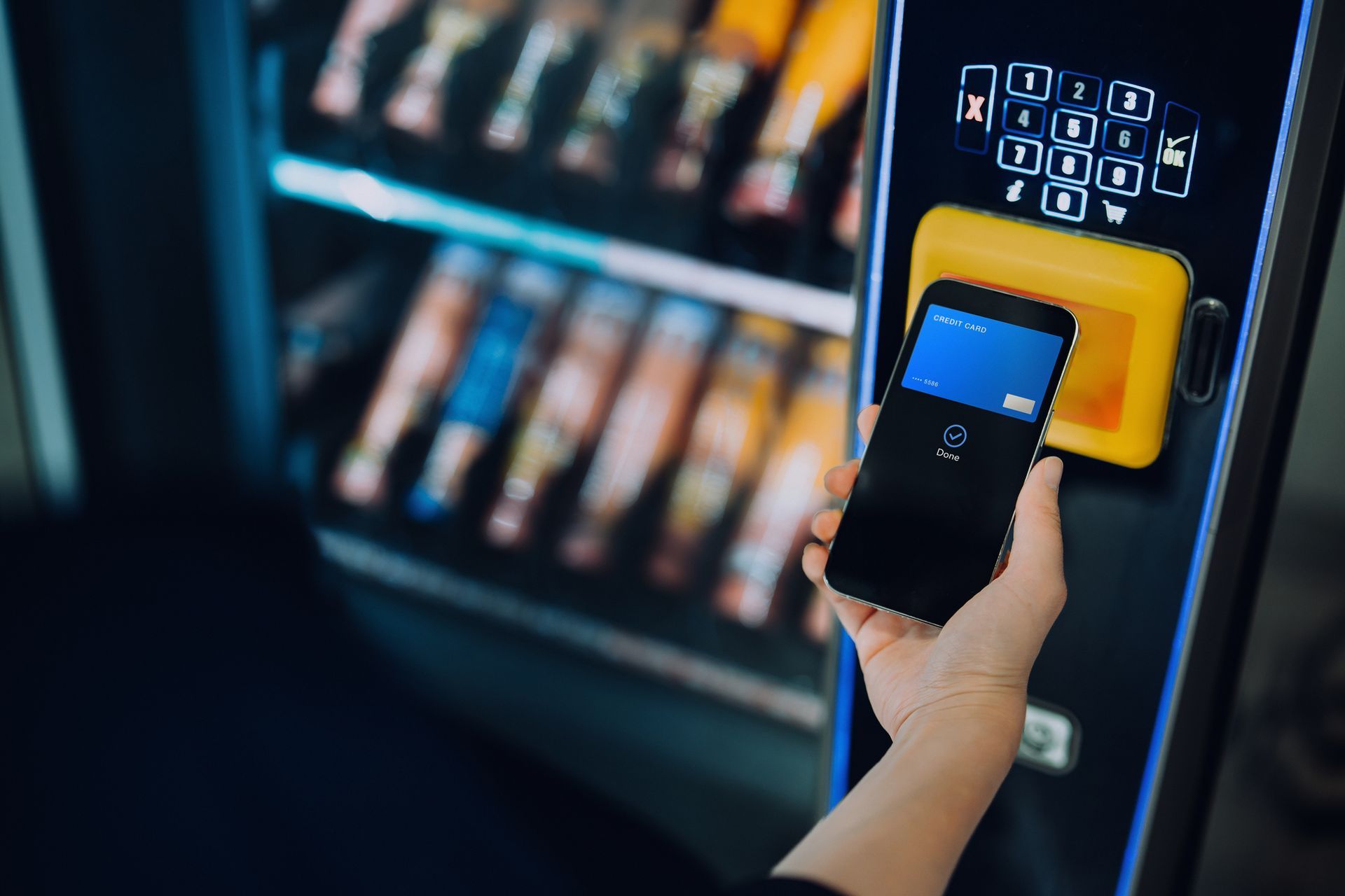 Woman paying at vending machine with contactless payment, provided by a machine company.