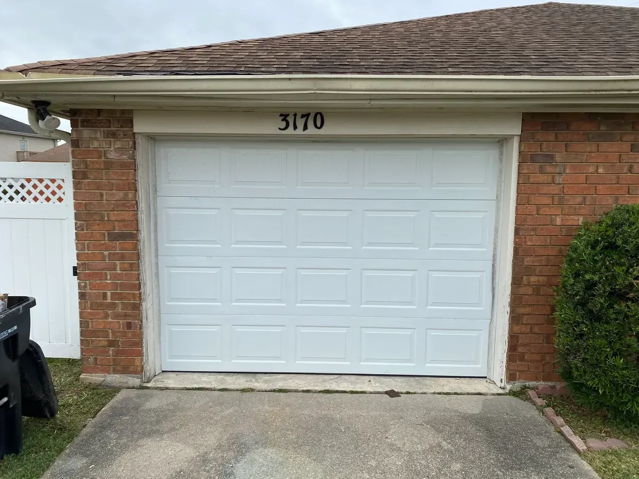 White garage door with number 3170 above, set in brick building.