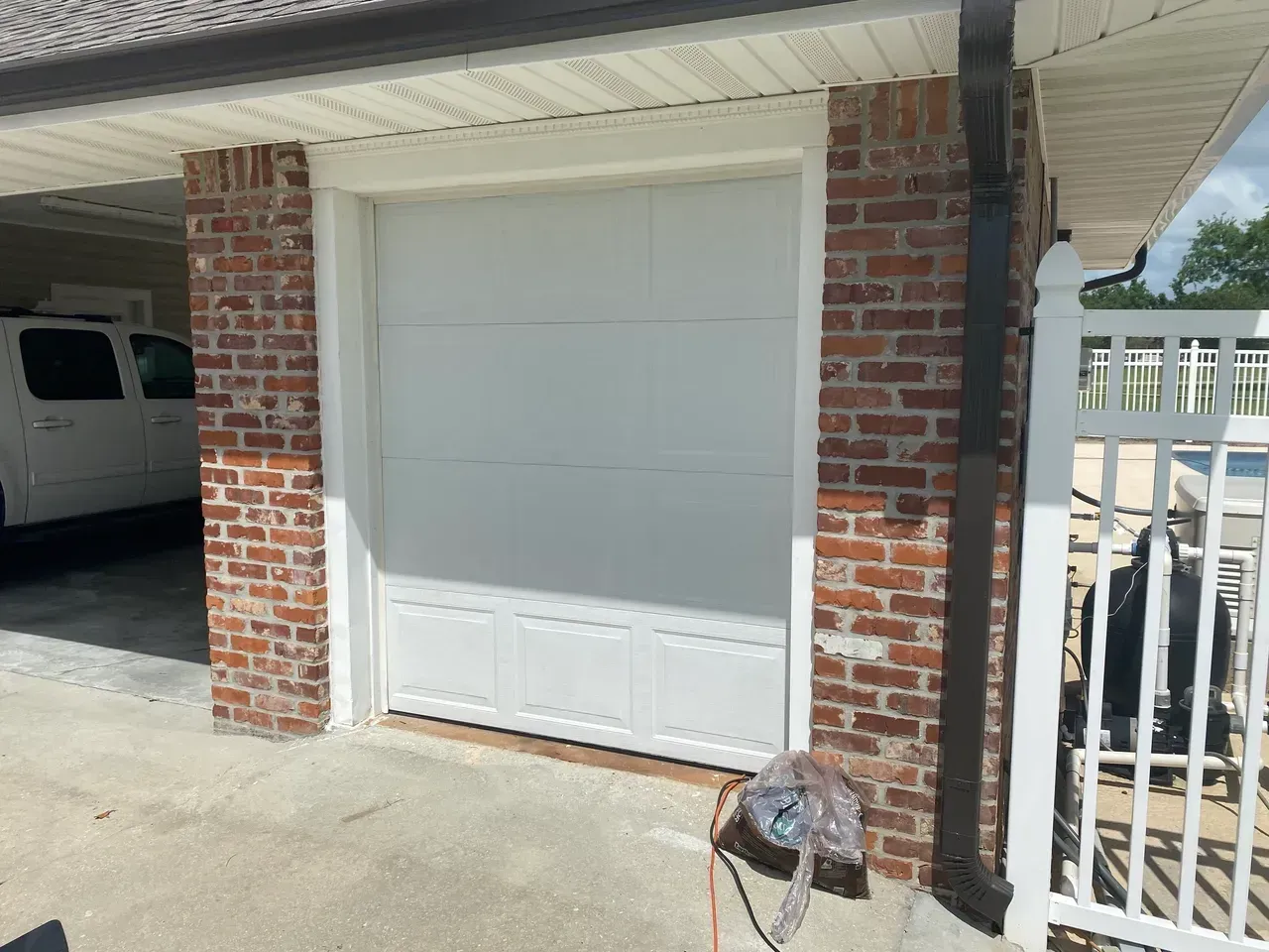 White garage door between brick columns with white trim.