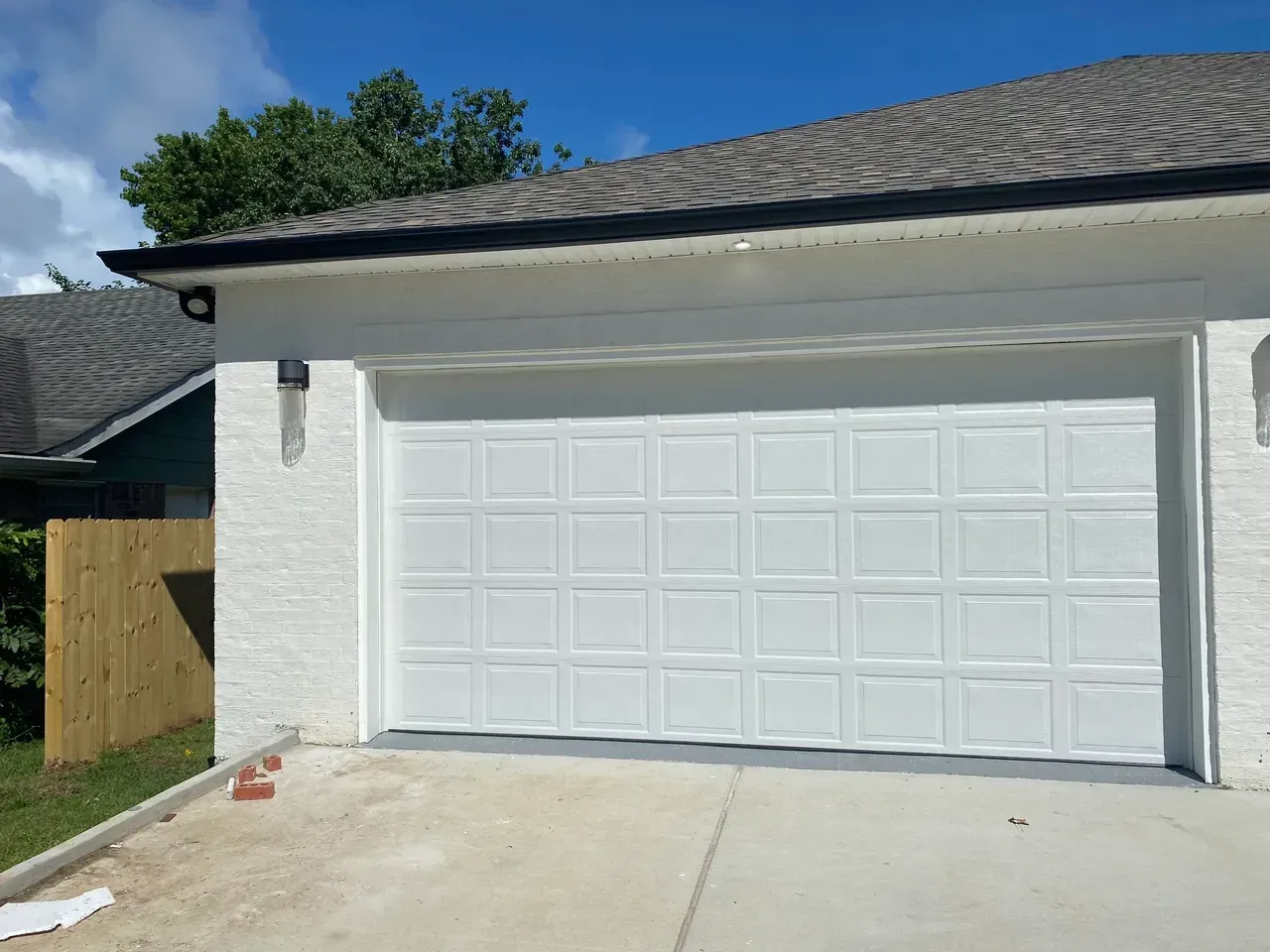 White garage door on a house with a gray roof and a clear blue sky.