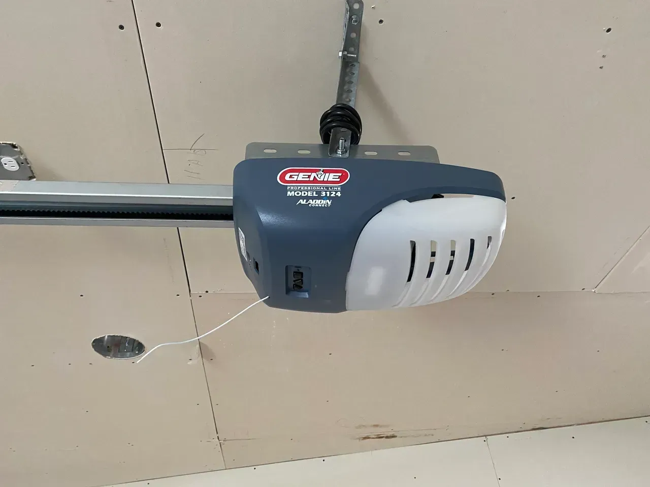 Genie garage door opener mounted on a ceiling. It is blue, white, and gray.