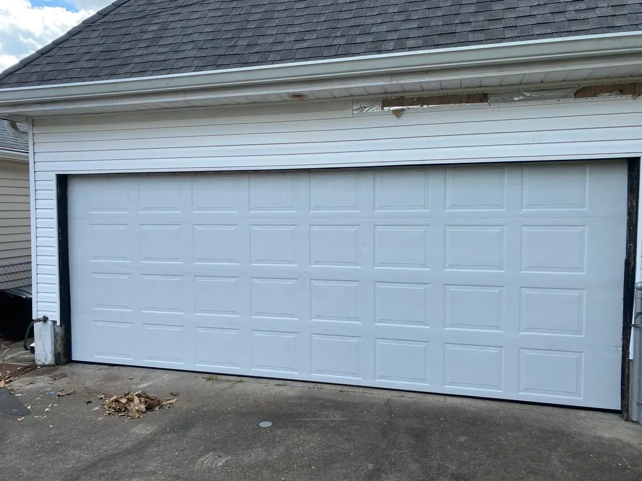 White garage door on a house with gray siding and roof.