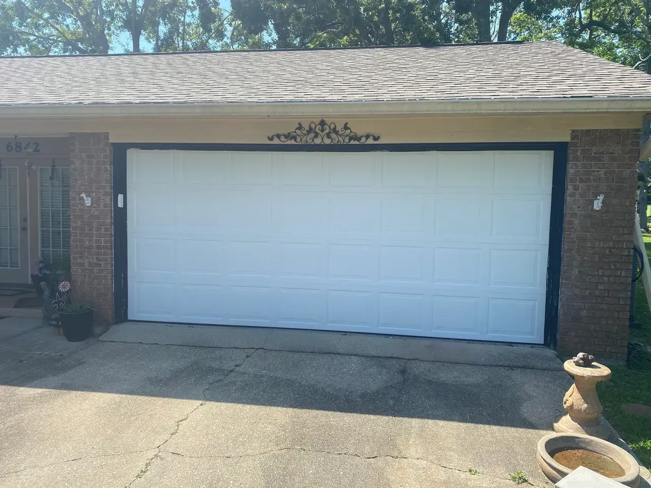 White garage door with black trim on a brick house.