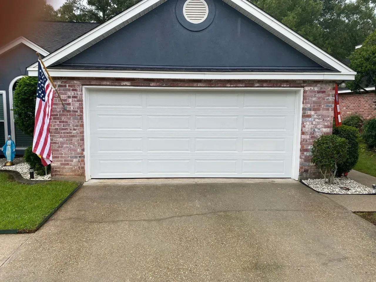 White garage door on brick house with US flag.