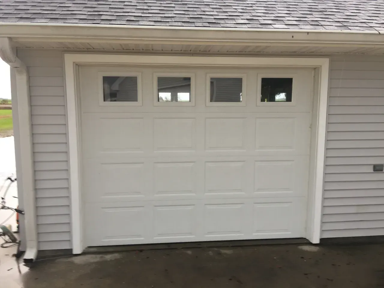 White garage door with four top windows in a light gray house.
