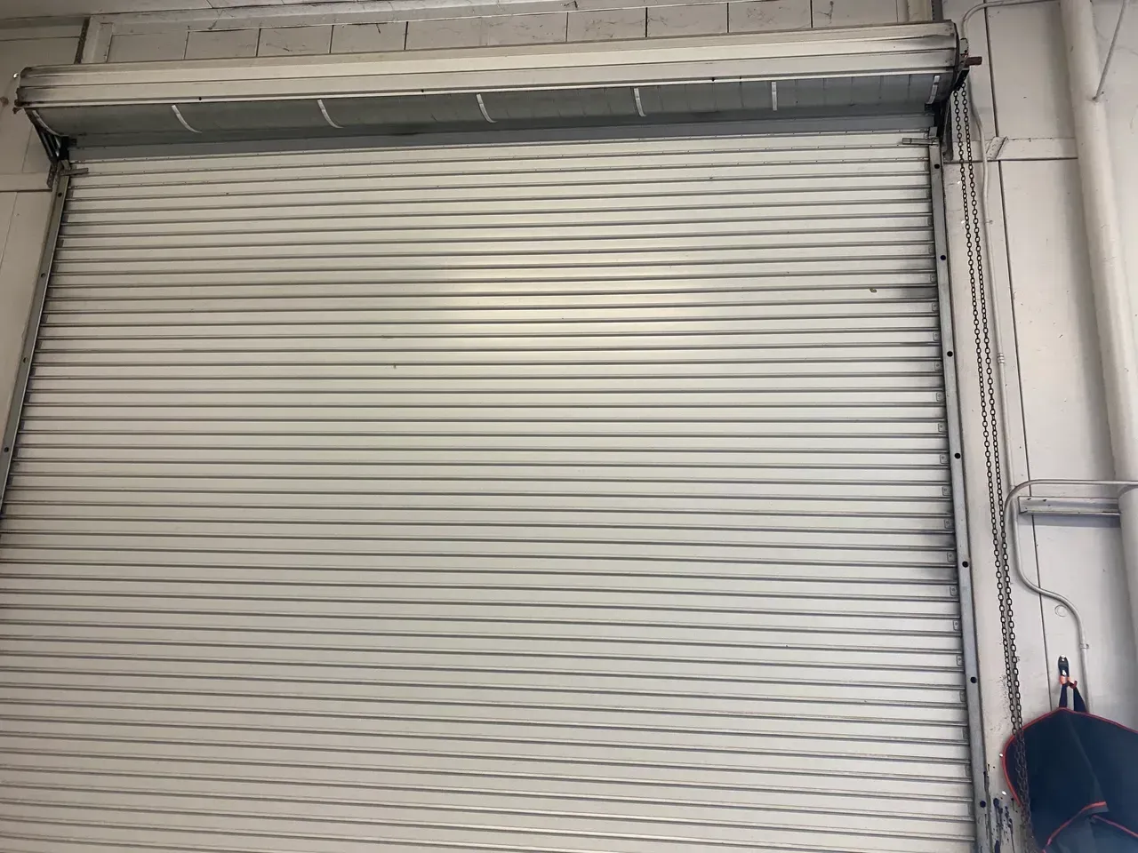 Gray, closed metal rolling door in a white-walled industrial space.